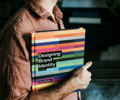 Person som håller boken Designing Brand Identity – inspiration inom varumärkesdesign
